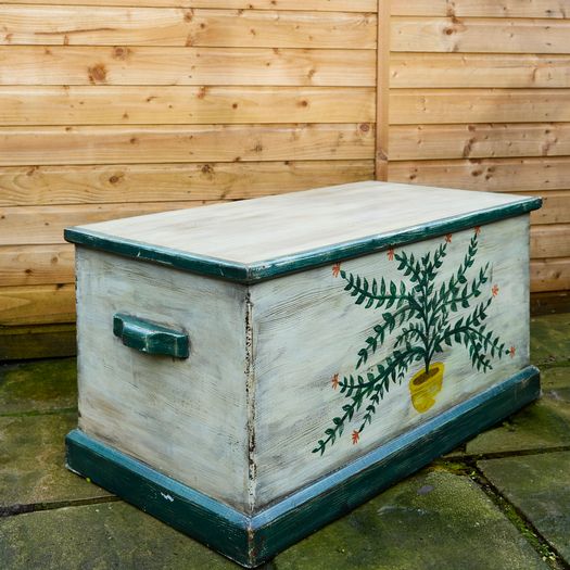 A hand-painted pine blanket box with botanical motif and hinged lid