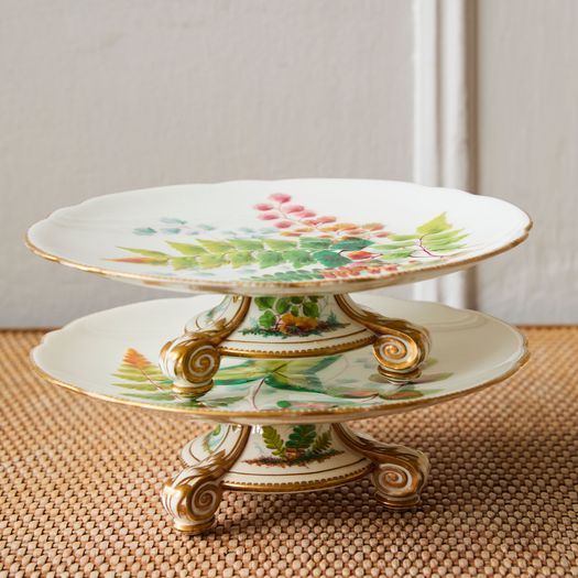 A pair of 19th century porcelain comports with a decorative leaf pattern on a gold three- footed stand.
