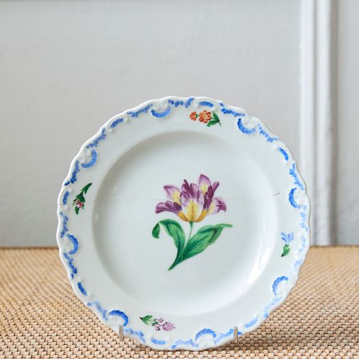 A set of six  early 20th century Meissen hand painted porcelain plates, each with a flower motif and scalloped, wavy rim with a blue border design.