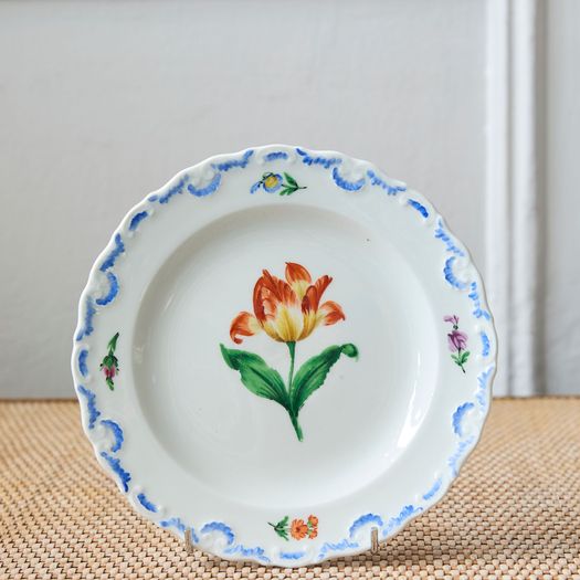 A set of six  early 20th century Meissen hand painted porcelain plates, each with a flower motif and scalloped, wavy rim with a blue border design.