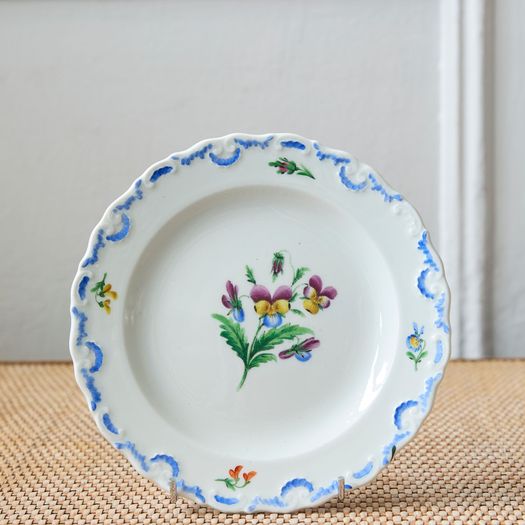 A set of six  early 20th century Meissen hand painted porcelain plates, each with a flower motif and scalloped, wavy rim with a blue border design.