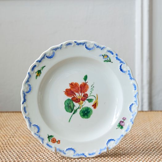A set of six  early 20th century Meissen hand painted porcelain plates, each with a flower motif and scalloped, wavy rim with a blue border design.