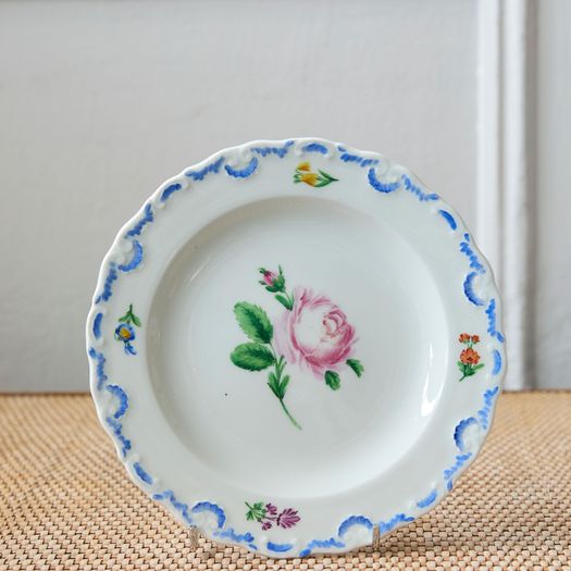 A set of six  early 20th century Meissen hand painted porcelain plates, each with a flower motif and scalloped, wavy rim with a blue border design.