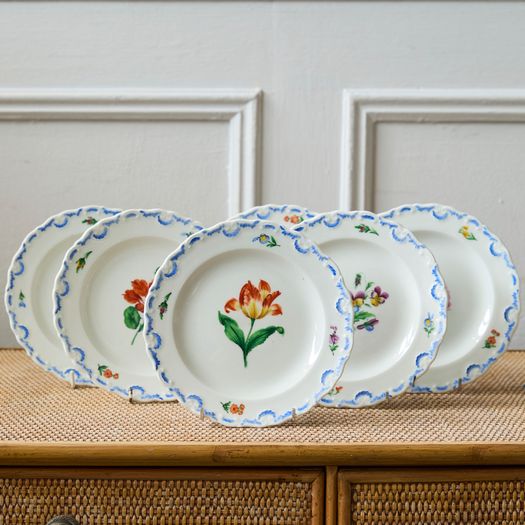 A set of six  early 20th century Meissen hand painted porcelain plates, each with a flower motif and scalloped, wavy rim with a blue border design.