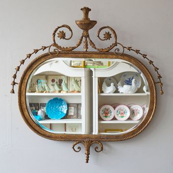 A 20th century Adam Style gilt metal framed oval mirror with bevelled plate.
